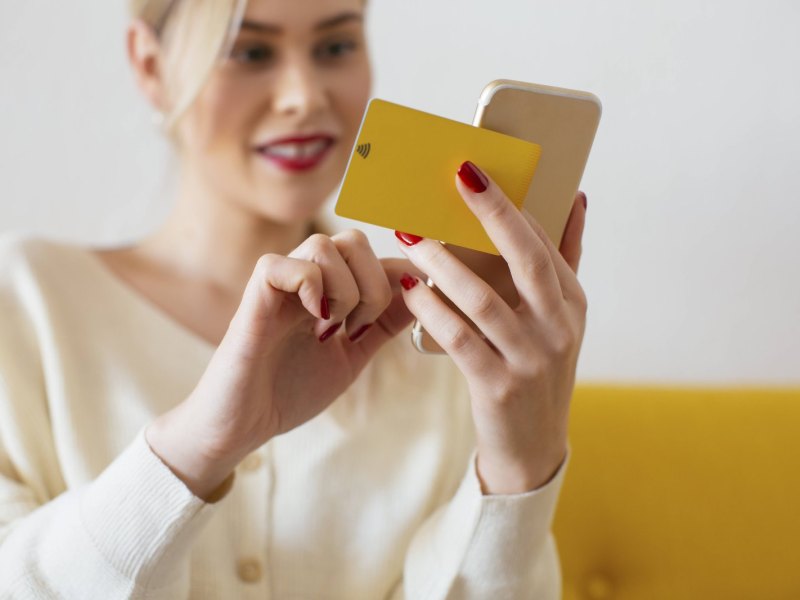 Frau hält Handy und Kreditkarte in der Hand.