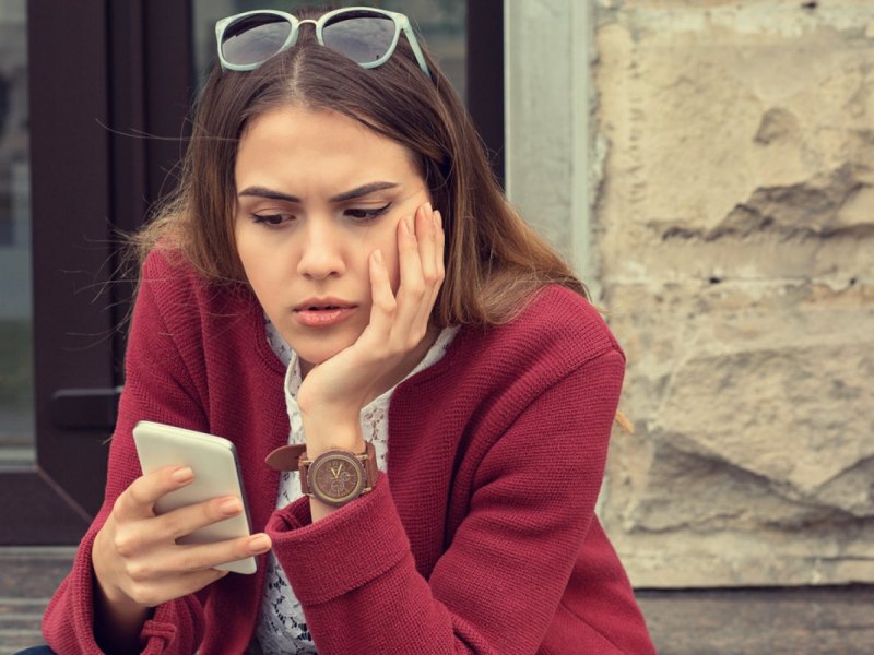 Frau schaut misstrauisch auf ihre Handy.