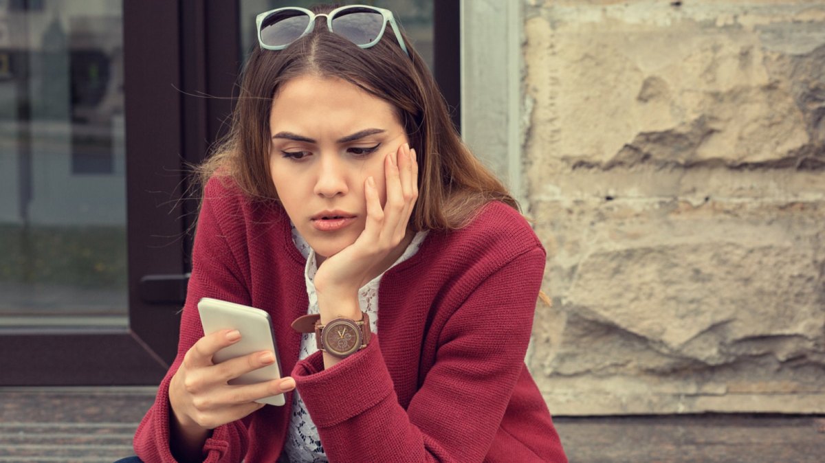 Frau schaut misstrauisch auf ihre Handy.