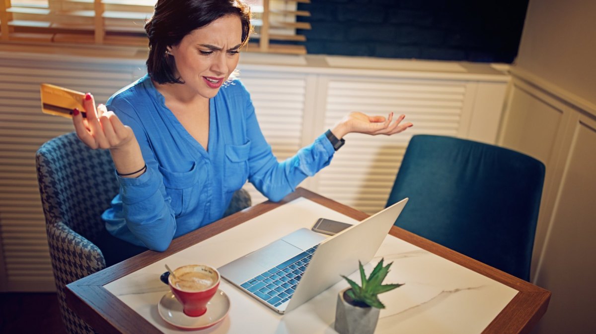 Frau mit Kreditkarte wütend am Laptop.