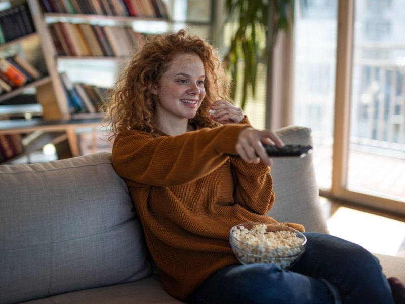 Frau mit Popcorn vor dem TV.