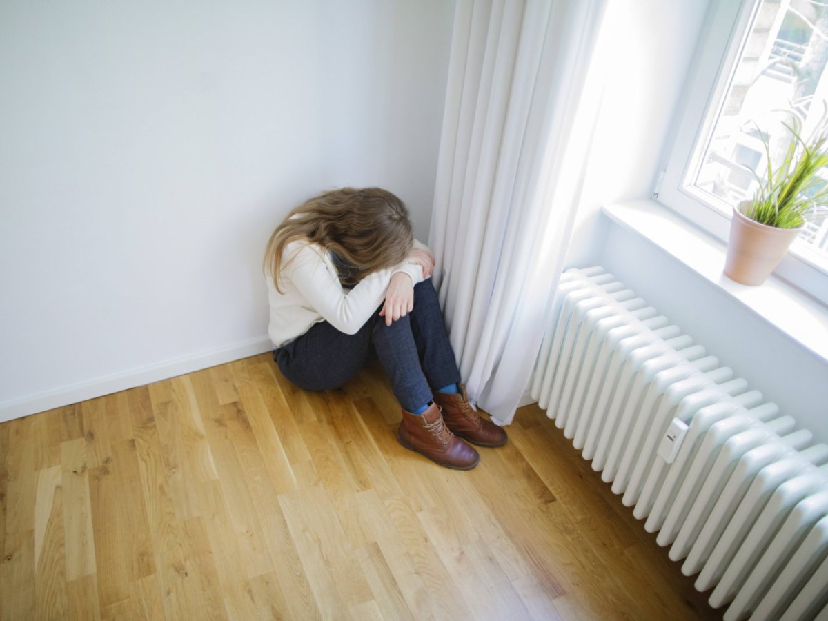 Eine Frau sitzt verängstigt auf dem Boden.