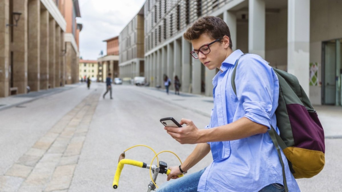 Ein Mann auf einem Fahrrad hält ein Smartphone in der Hand.