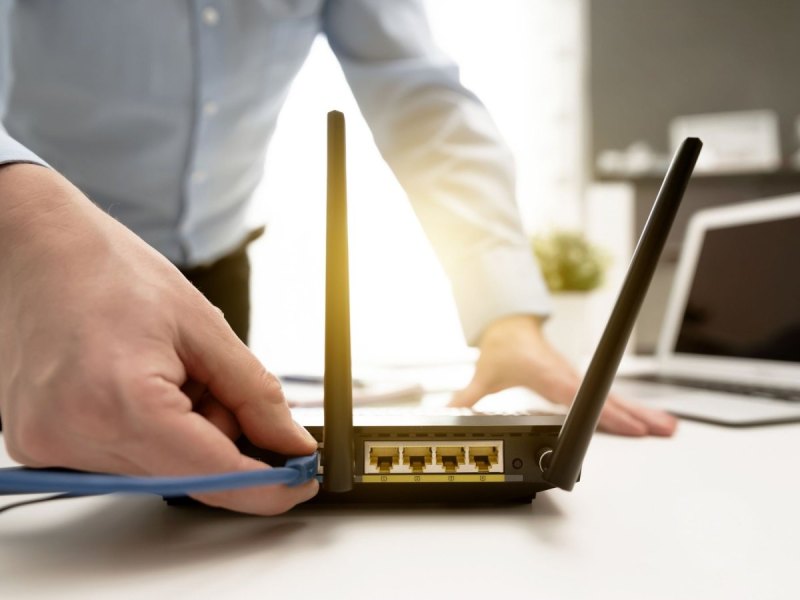 Mann stöpselt WLAN an Router an