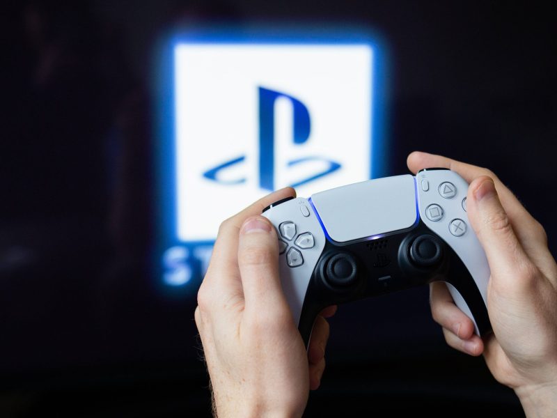 Controller von PS5 vor Fernseher mit Logo