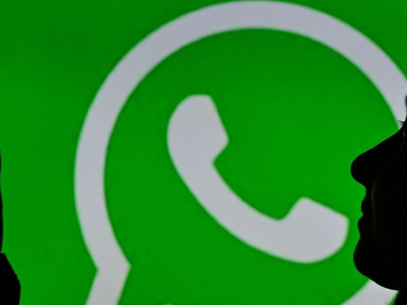 Frau mit Smartphone vor einem WhatsApp-Logo