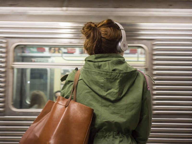 Frau mit Kopfhörern vor Bahn