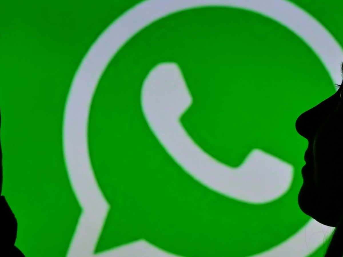 Frau mit Smartphone vor einem WhatsApp-Logo