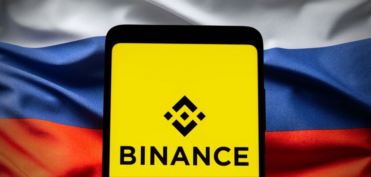 Binance-Logo vor einer Russland-Flagge