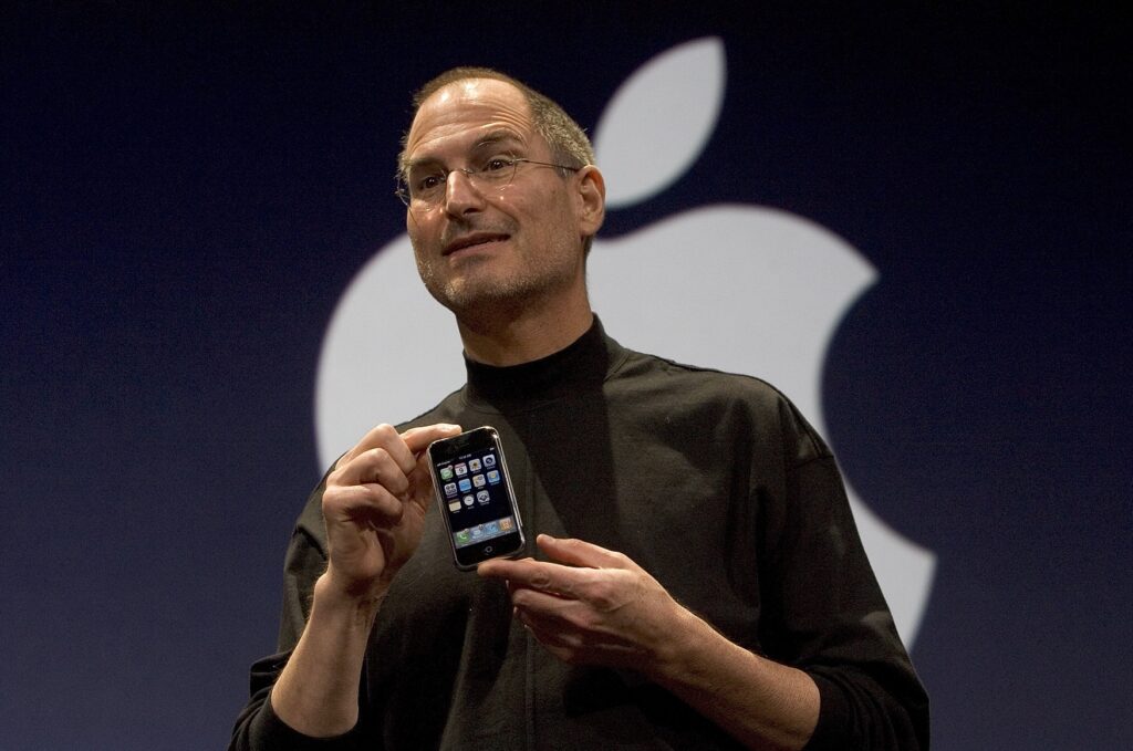 Mann hält ein Smartphone vor einem Apple-Logo