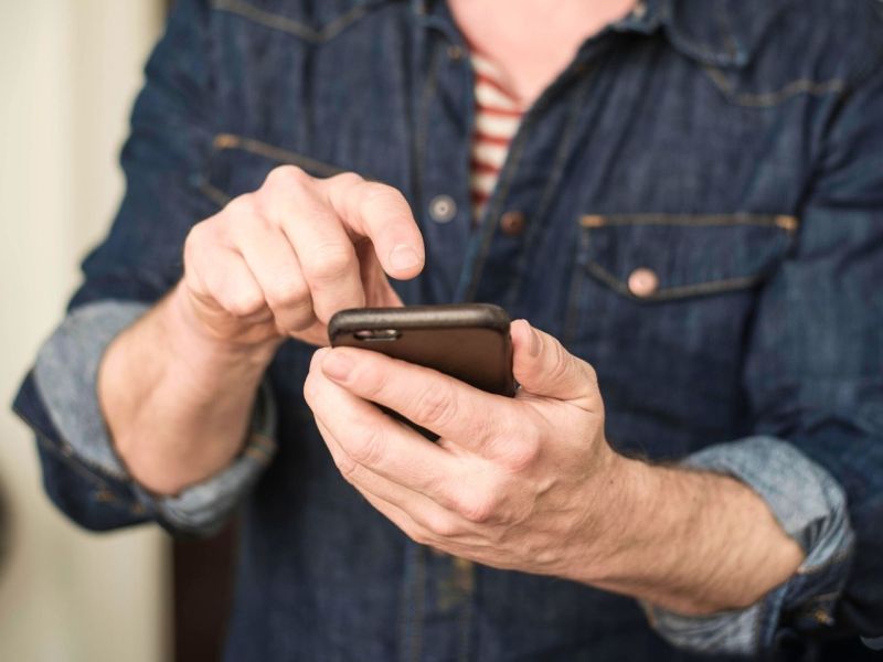 Mann tippt mit Finger auf sein Smartphone.