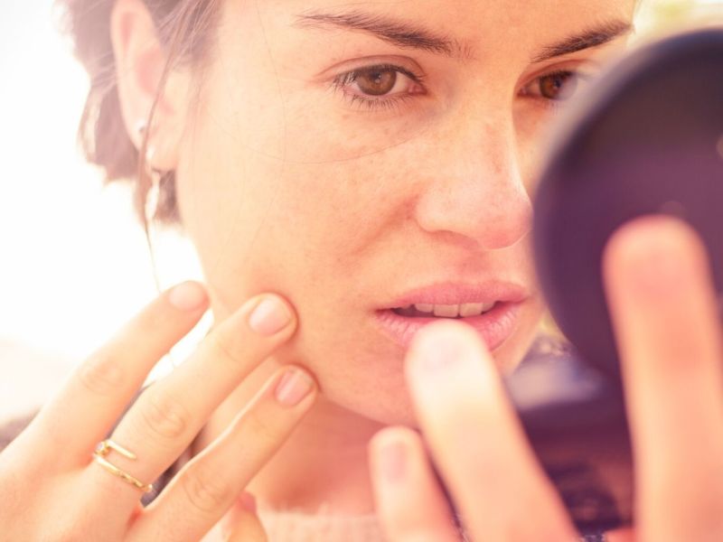 Frau schaut in einen Makeup-Spiegel