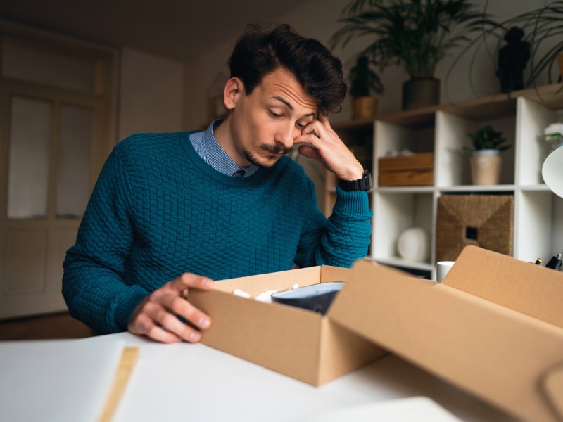 Mann öffnet Paket und ist nicht erfreut.