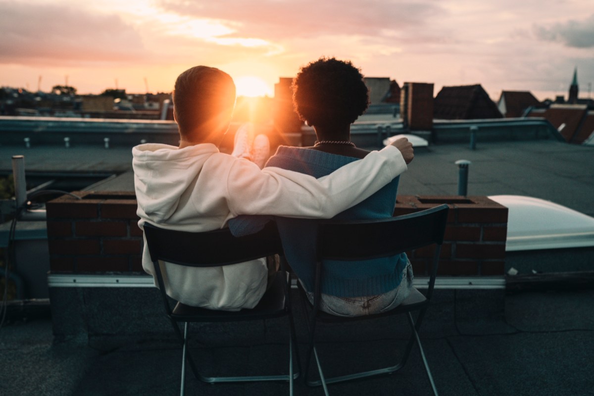 Zwei Personen auf dem Dach beobachten den Sonnenuntergang