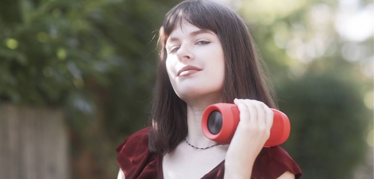 Frau hält Bluetooth-Lautsprecher in der Hand