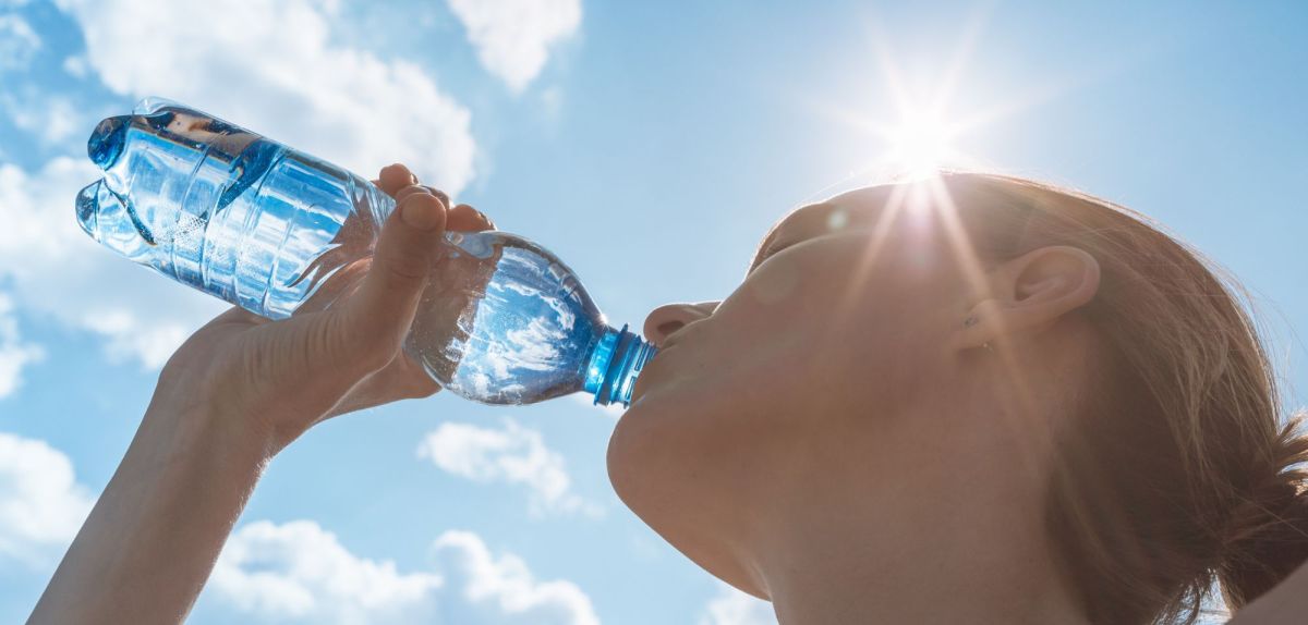 Frau trinkt Wasser aus einer Flasche.