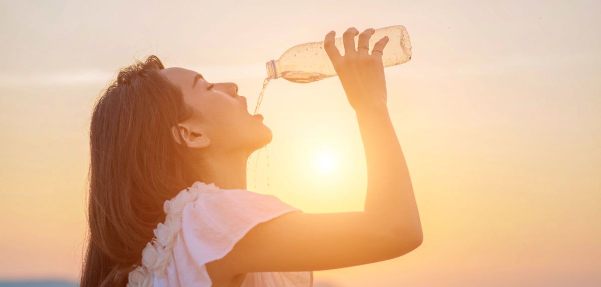 Frau lässt Wasser aus einer Flasche in ihren Mund laufen