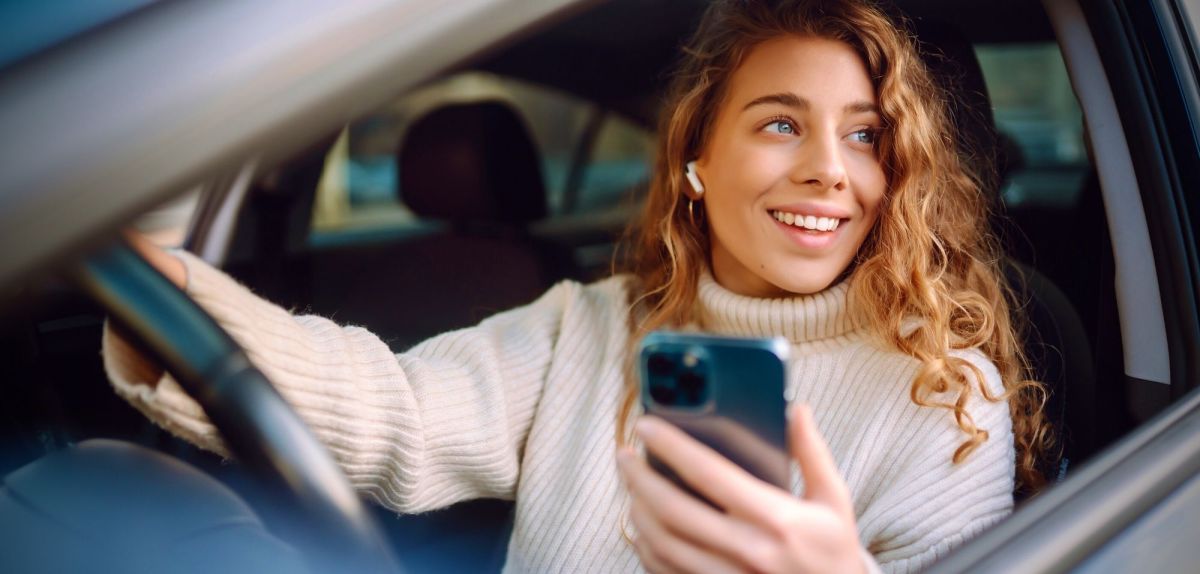 Frau mit Handy im Auto