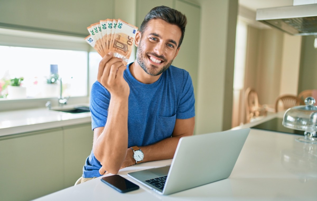 Mann mit Geld in der Hand am Laptop