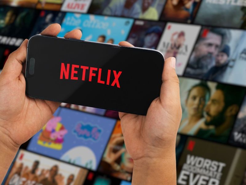 person hält handy mit netflix logo