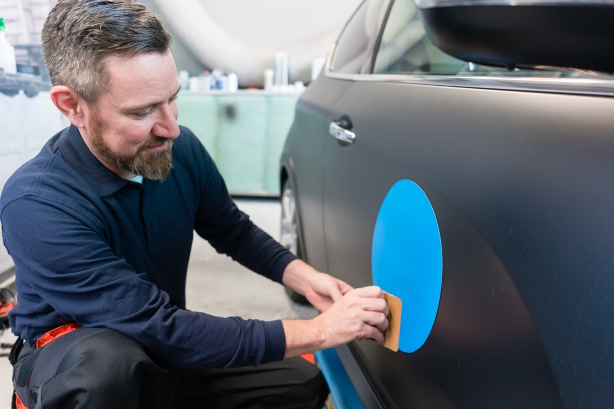 Mann bringt Aufkleber am Auto an