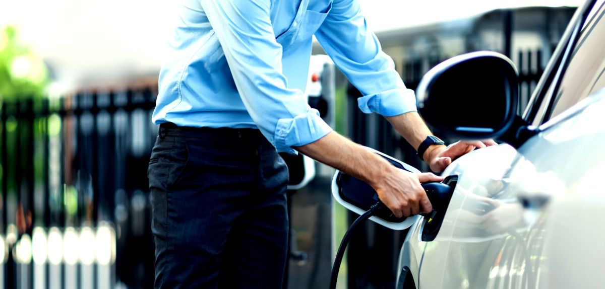 Mann lädt ein Elektroauto auf.