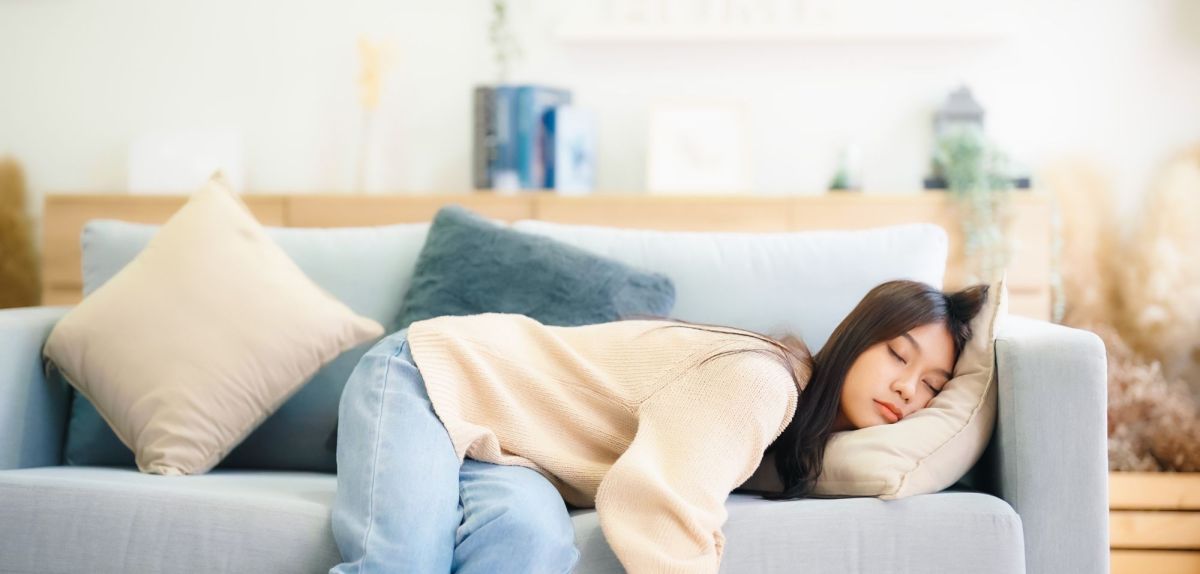 Frau hält auf einem Sofa ein Nickerchen.