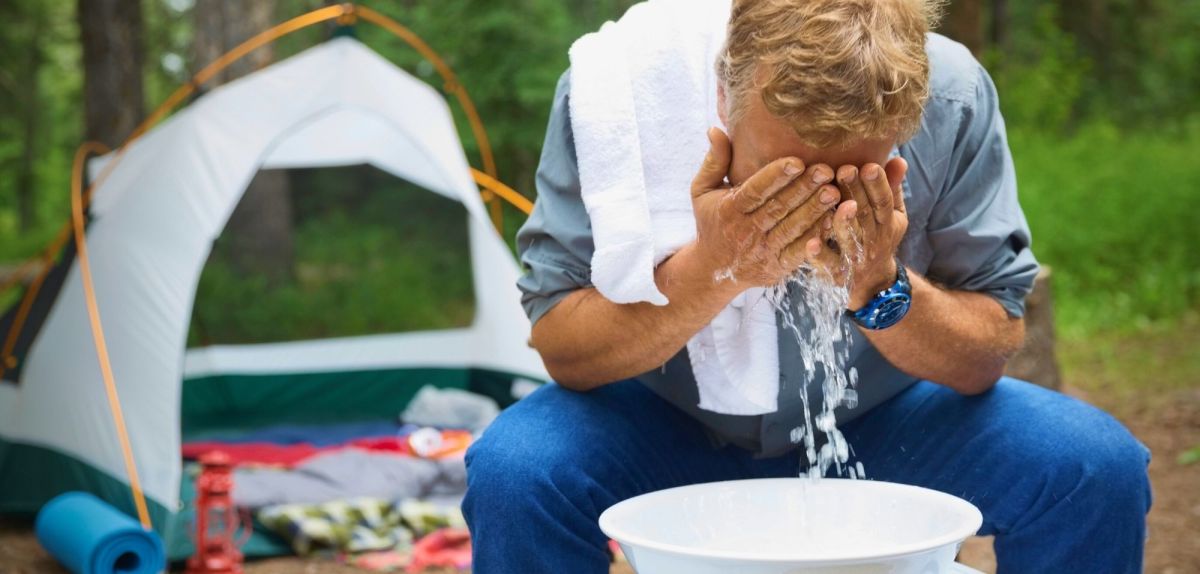 Mann wäscht sich das Gesicht beim Camping