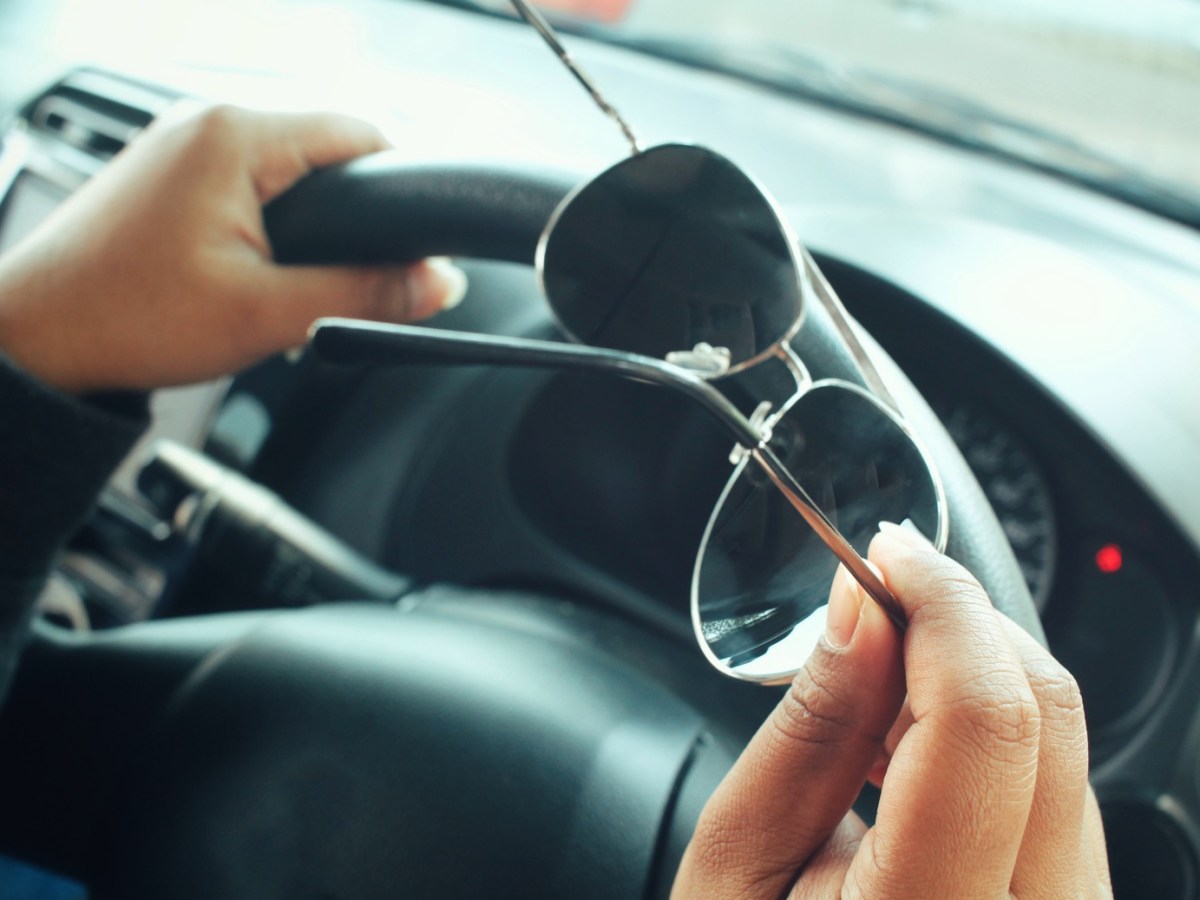 Mann am Lenkrad hält Sonnenbrille in der Hand