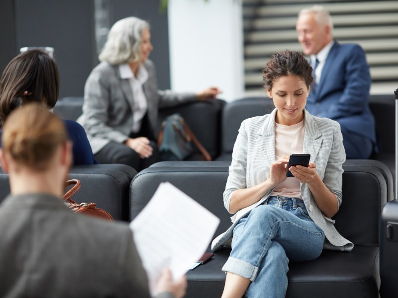 Frau surft am Handy am Flughafen