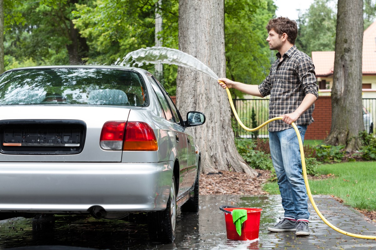 Auto wird im Garten von Mann gewaschen