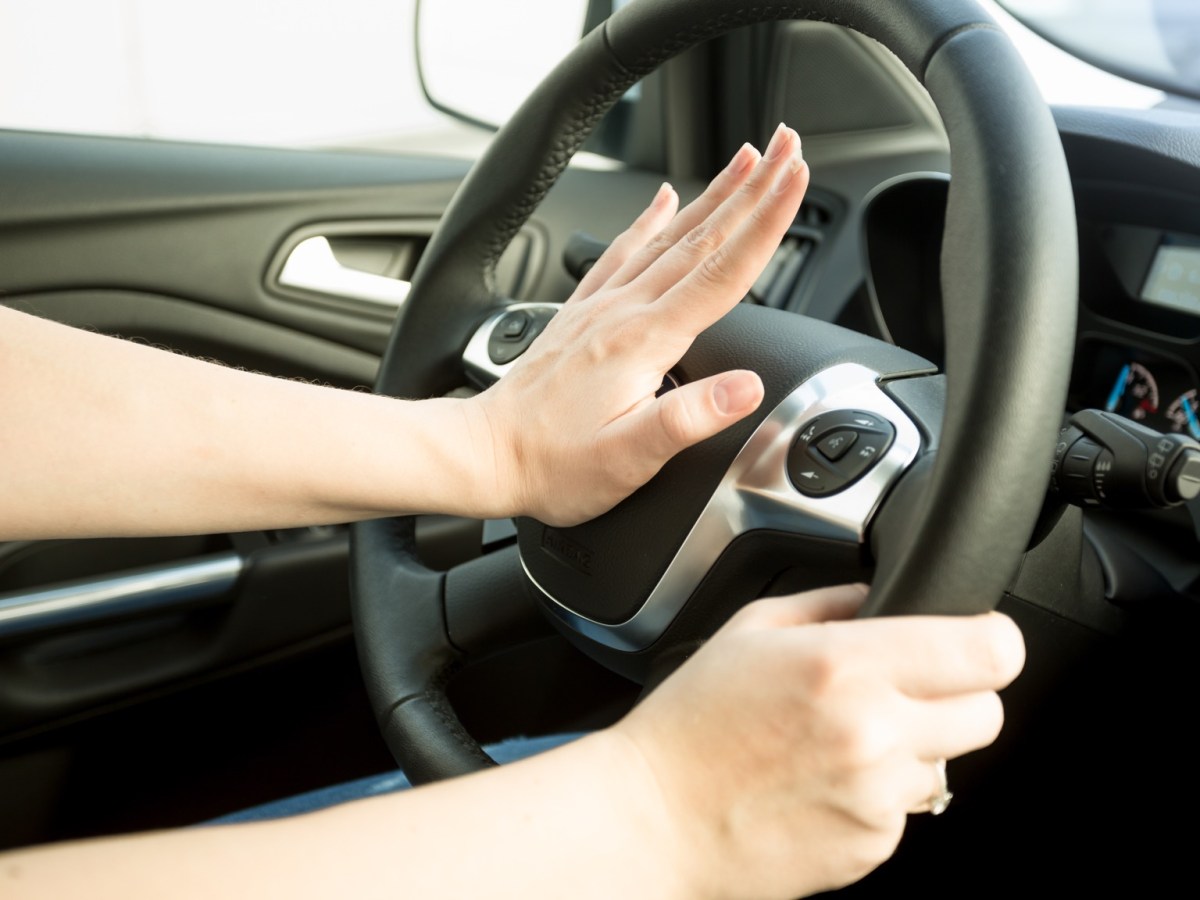 Frau drückt im Auto auf die Hupe