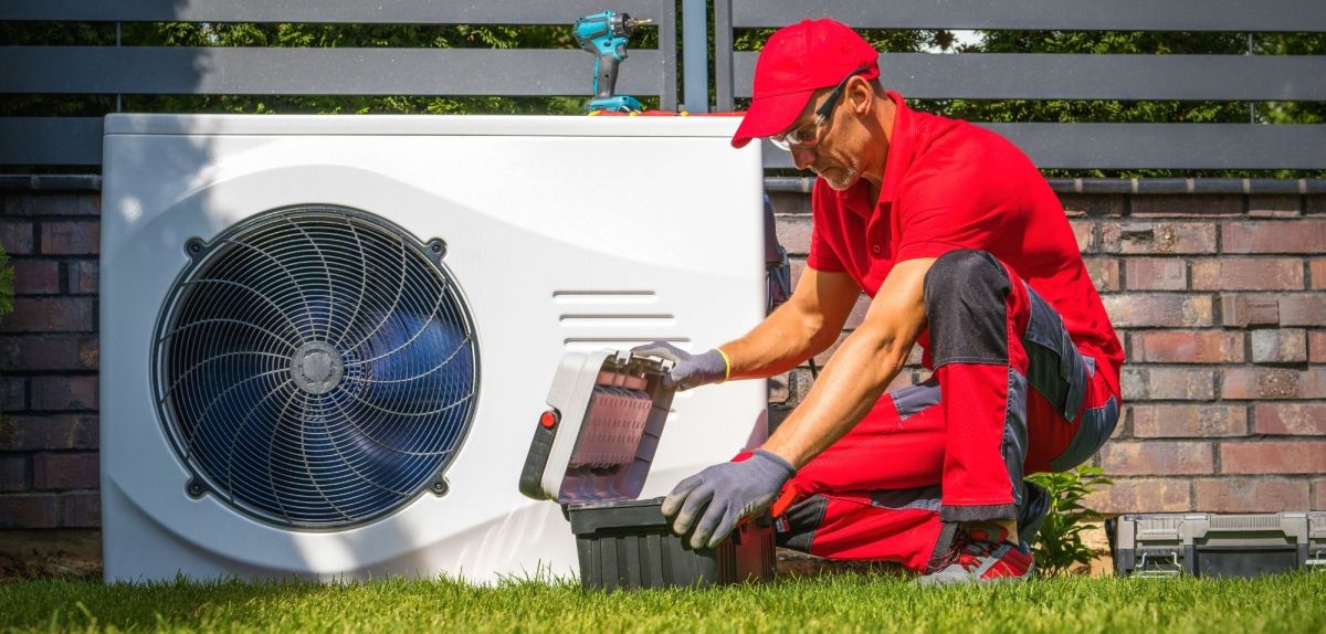 Fachkraft installiert Wärmepumpe im Garten