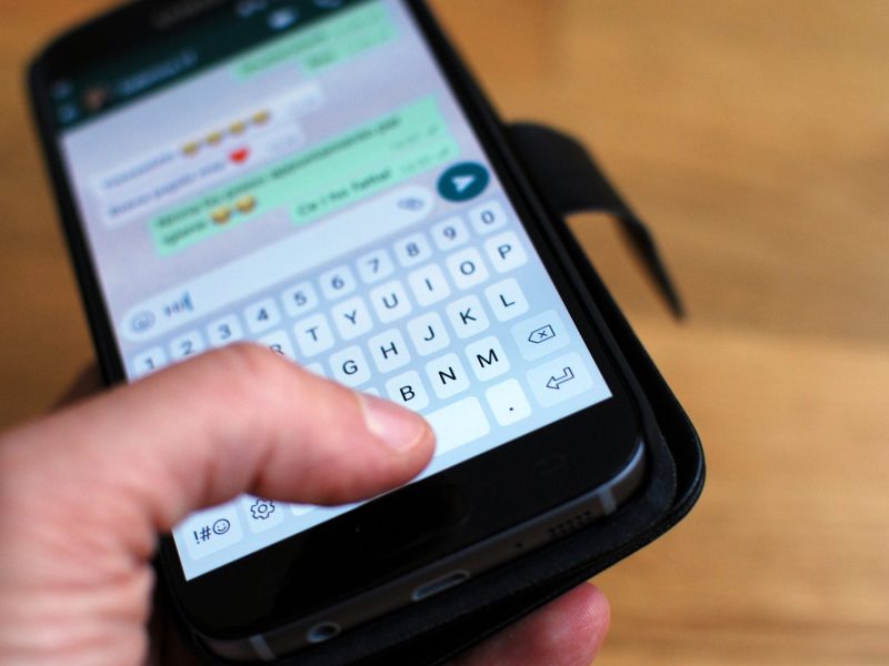 Person hält Handy mit WhatsApp in der Hand.