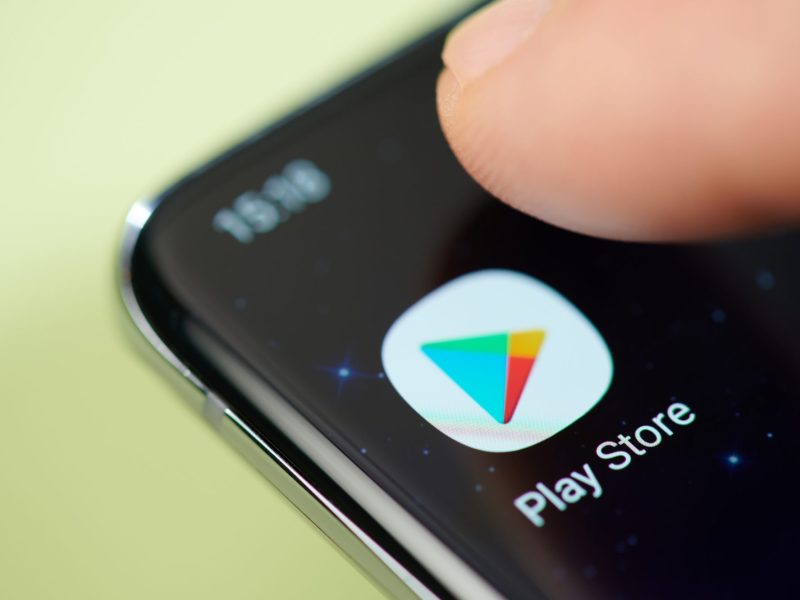 Finger tippt auf Google Play Store-Icon auf Smartphone.