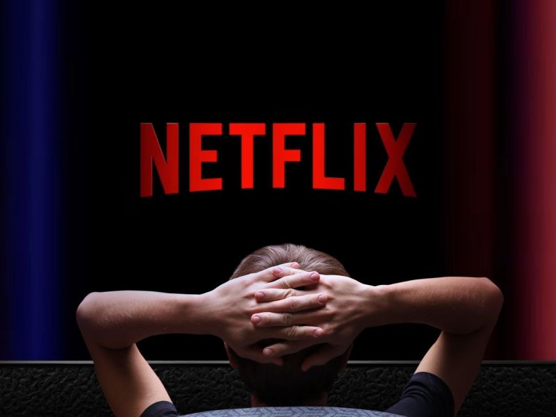 Person sitzt vor einem Fernseher mit dem Netflix-Logo auf dem Bildschirm.