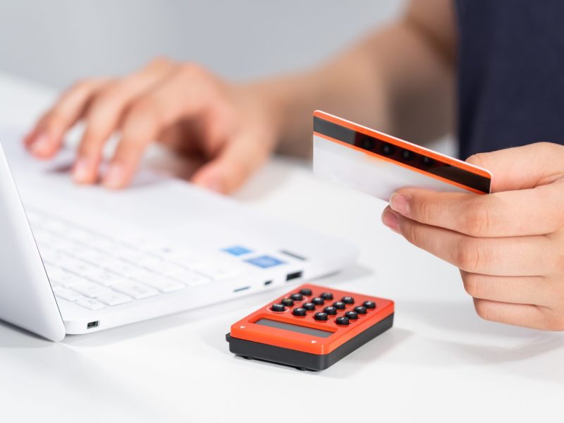 Person betreibt Online Banking am Laptop mit Kreditkarte und Tan Maschine.