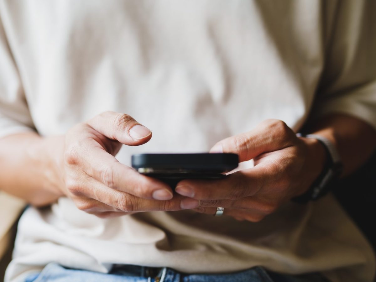 Eine Person tippt mit beiden Händen am Smartphone.