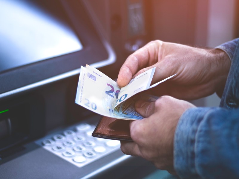 Mann hebt Geld am Automaten ab