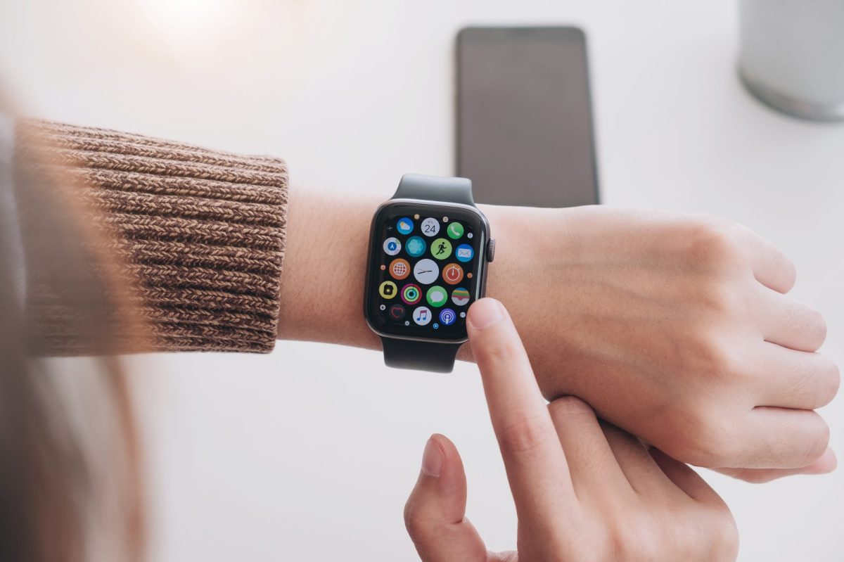 Apple Watch wird mit einem Finger angetippt, ist an einem Handgelenk befestigt.