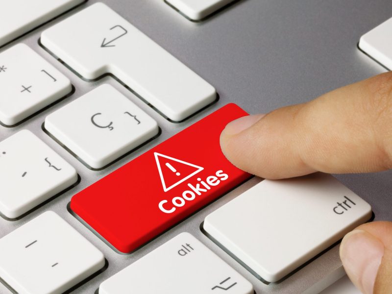 Eine Person drückt eine mit "Cookies" beschriftete Taste auf einer Tastatur.