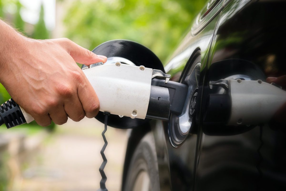 Ein Mann lädt sein schwarzes Elektroauto auf.