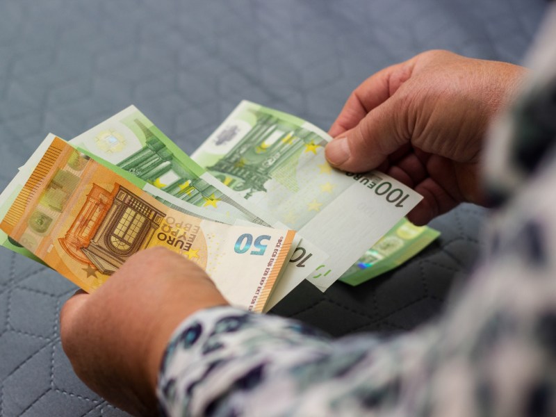 Mann zählt Bargeld in Scheinen