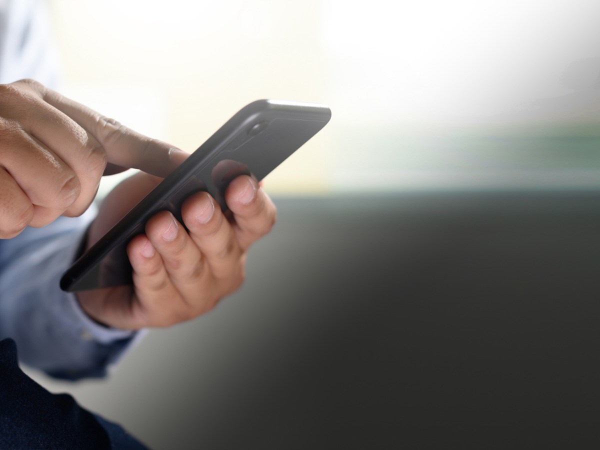 Mann hält ein Handy in der Hand und tippt auf den Bildschirm