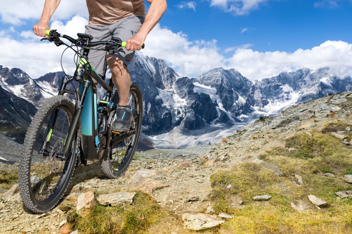 Mann fährt auf E-Fatbike durch die Berge.