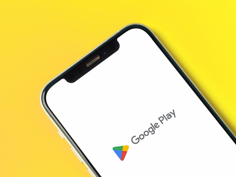 Google Play Store-Logo auf einem Handy vor gelbem Hintergrund