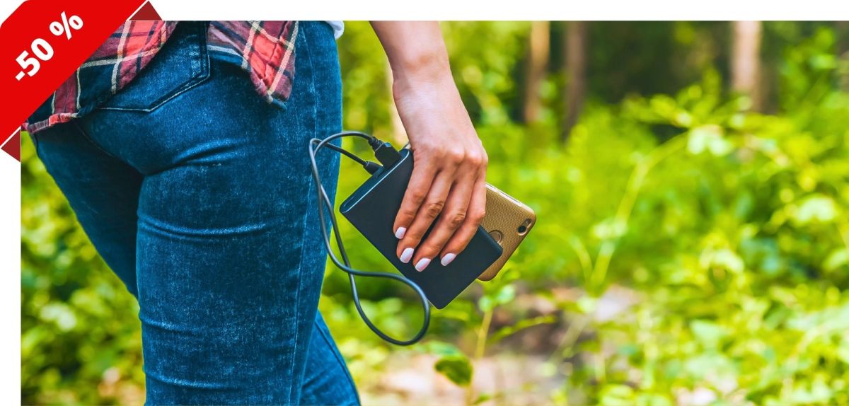 Person läuft mit Powerbank und Smartphone durch einen Wald