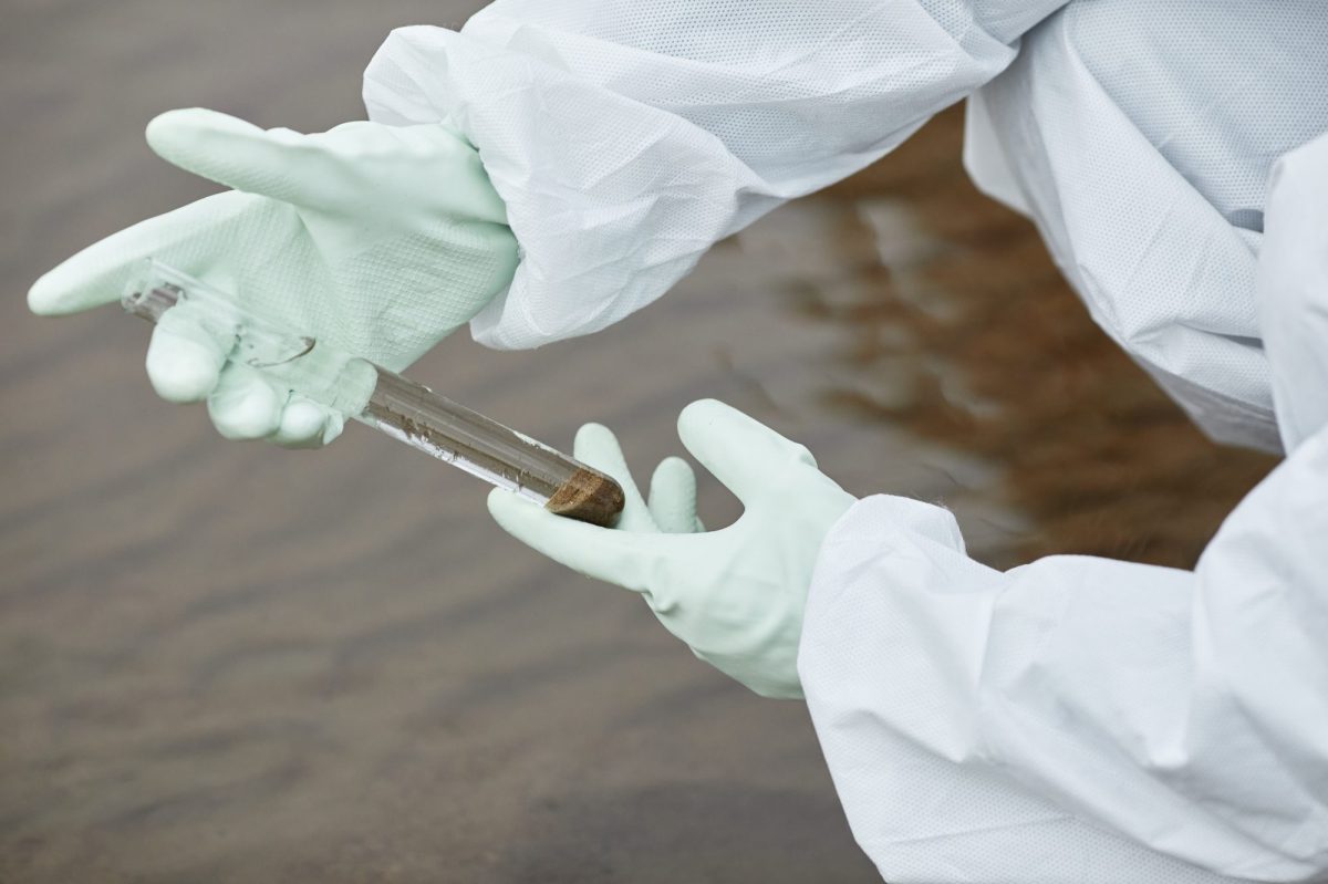 Eine Person mit weißen Handschuhen hält eine Wasserprobe in der Hand.