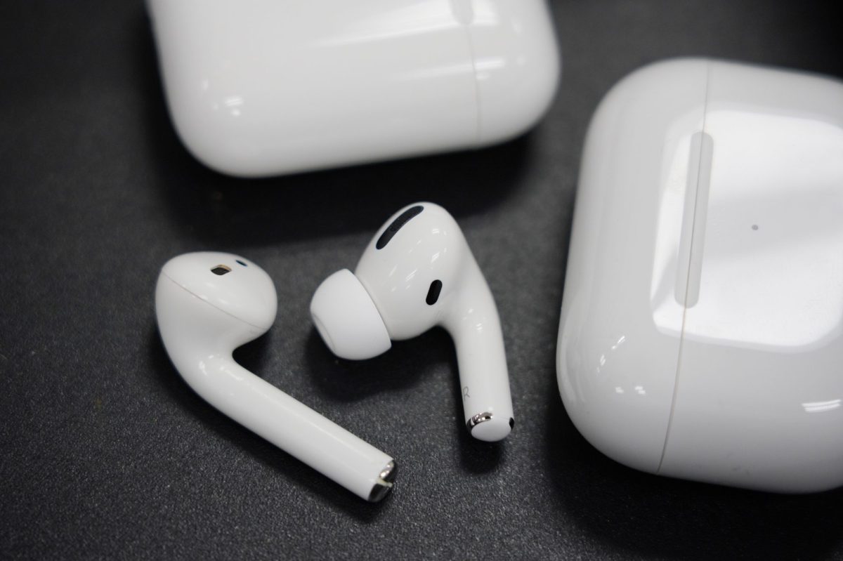 Zwei AirPods-Kopfhörer liegen neben der Hülle auf einem Schwarzen Hintergrund.