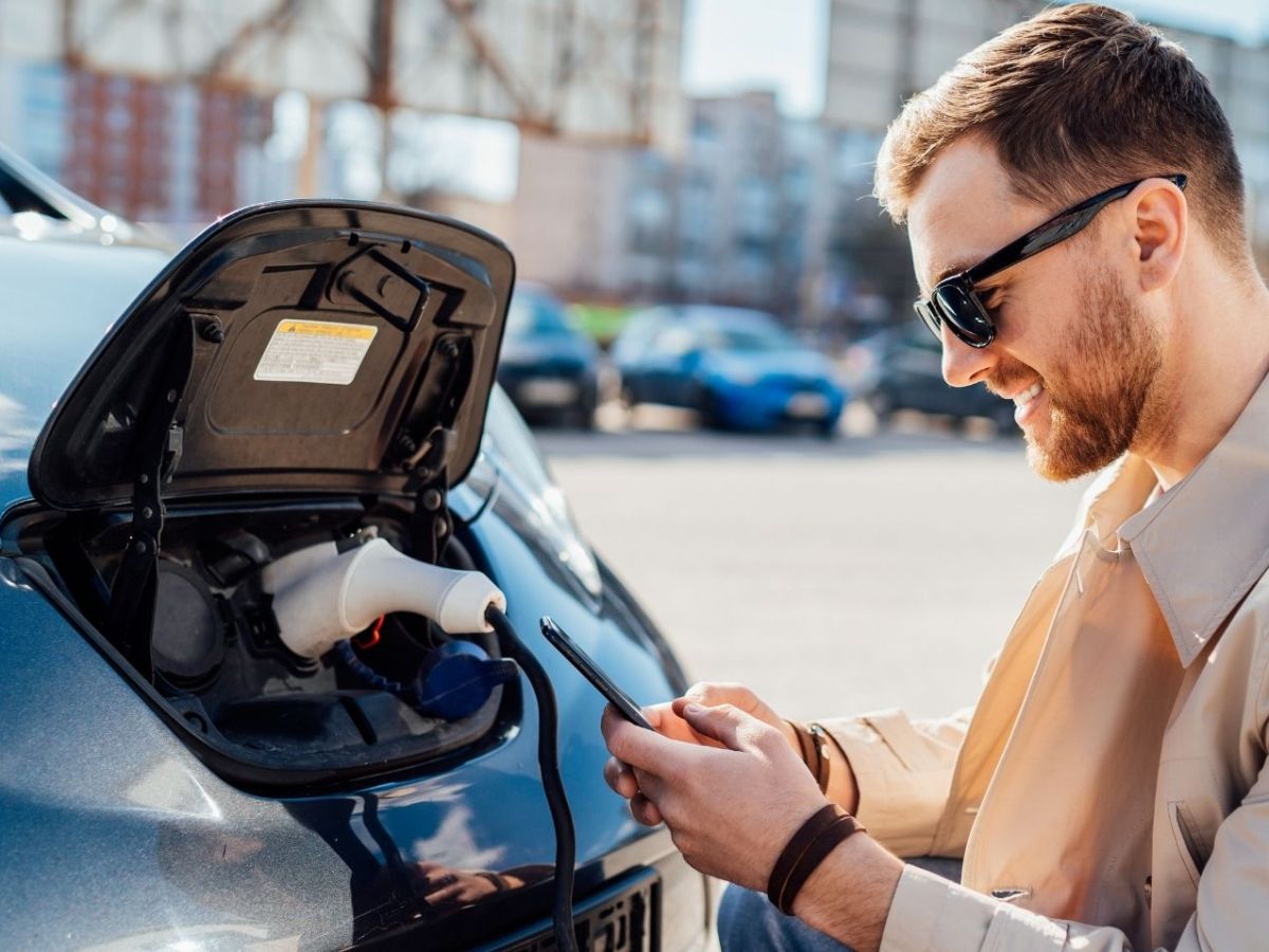 Elektroauto-Fahrer nutzt Apps auf dem Smartphone.